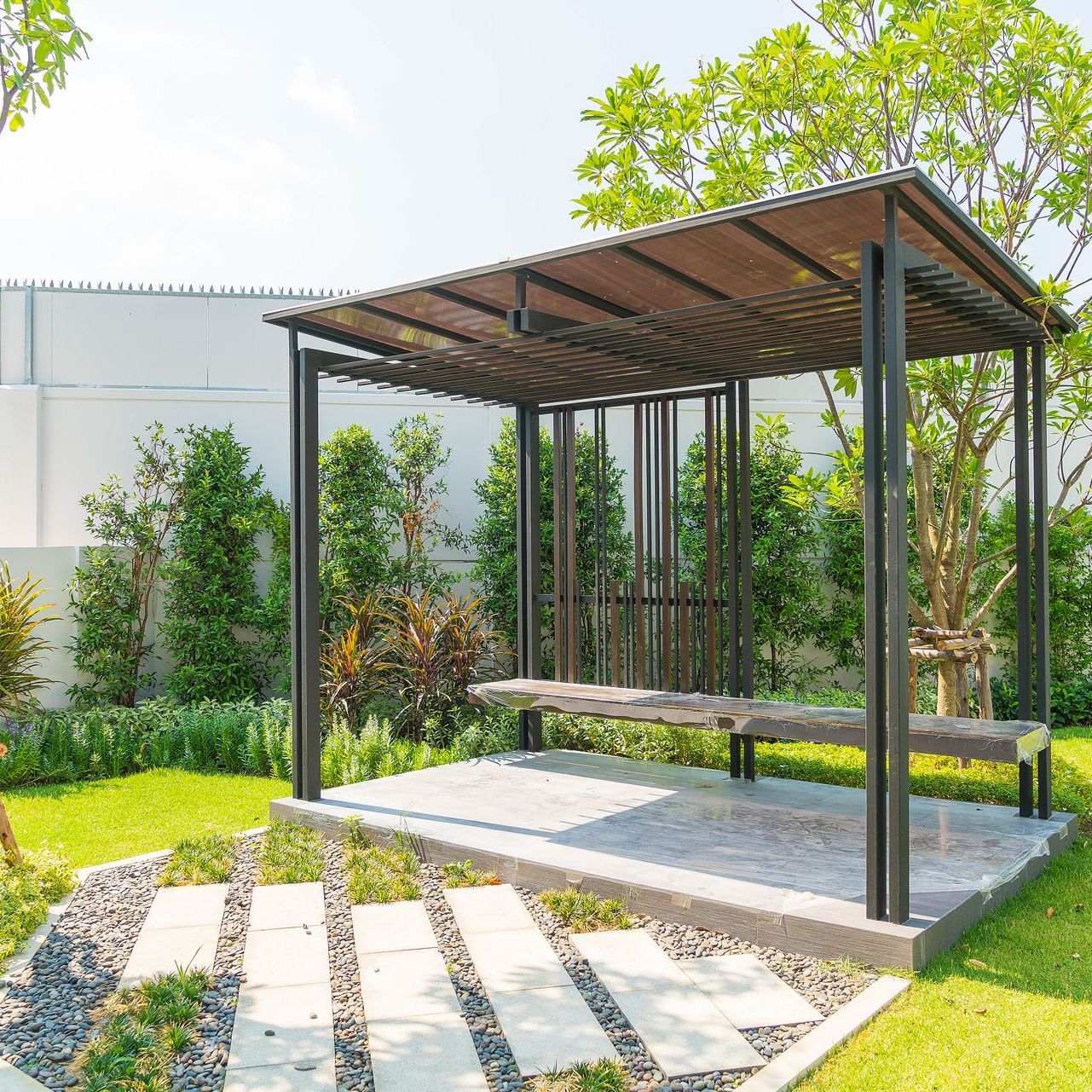 A pergola with a bench in the middle of a garden.