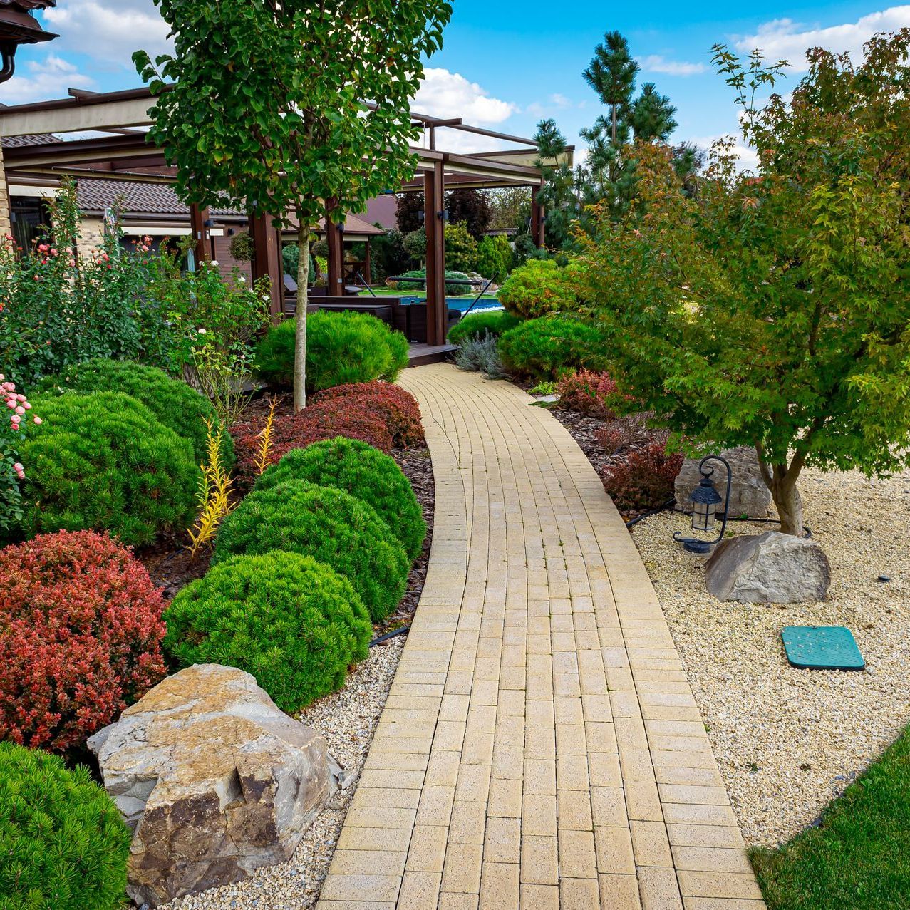 A brick walkway surrounded by trees and bushes in a garden.