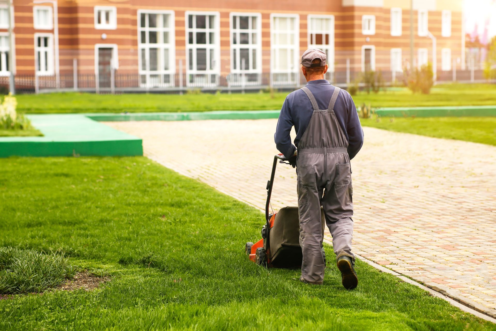 A man is mowing the grass in a park with a lawn mower.