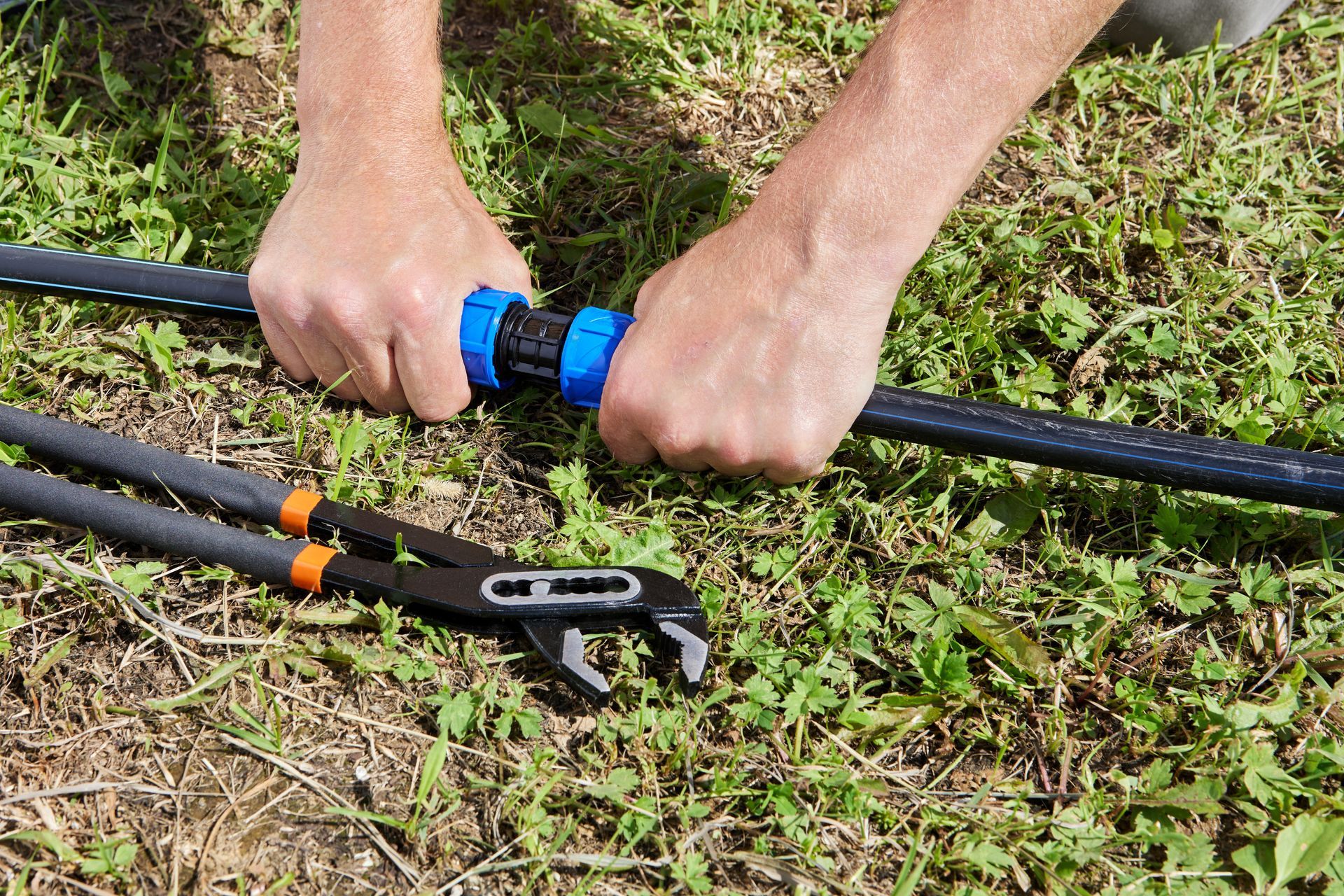 A person is working on a pipe with a pair of pliers.
