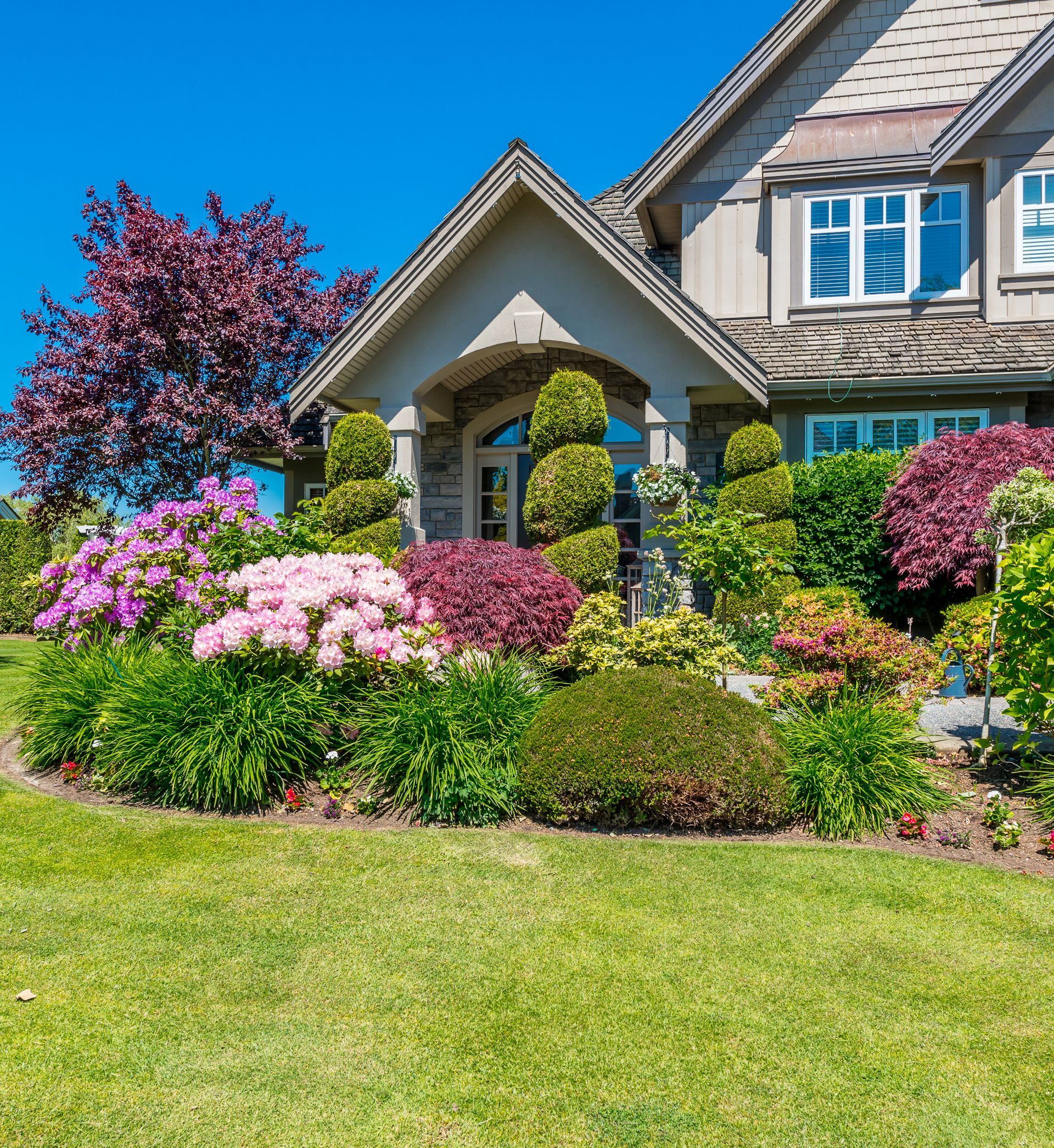 A large house with a lush green lawn and flowers in front of it.