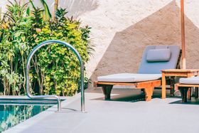 A swimming pool with lounge chairs and umbrellas next to it.