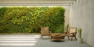 A patio with chairs and a table in front of a green wall.