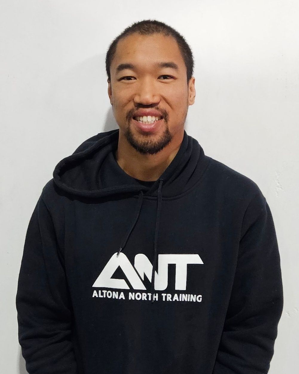 A man wearing a black ant hoodie smiles for the camera