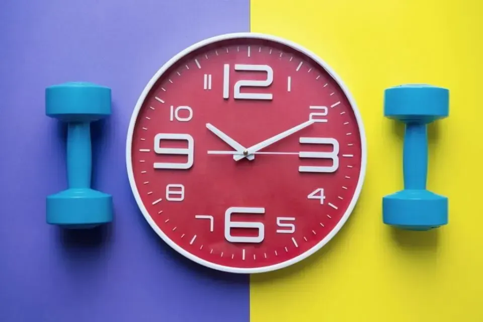 A red clock and two blue dumbbells on a blue and yellow background.