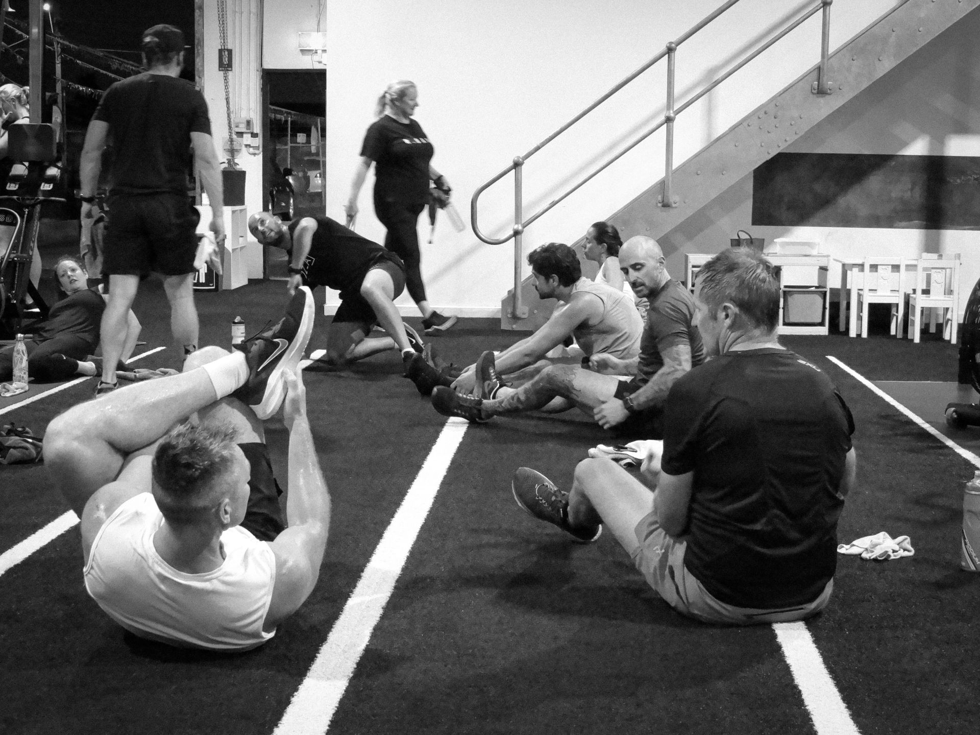 A group of people are doing exercises on the floor in a gym.