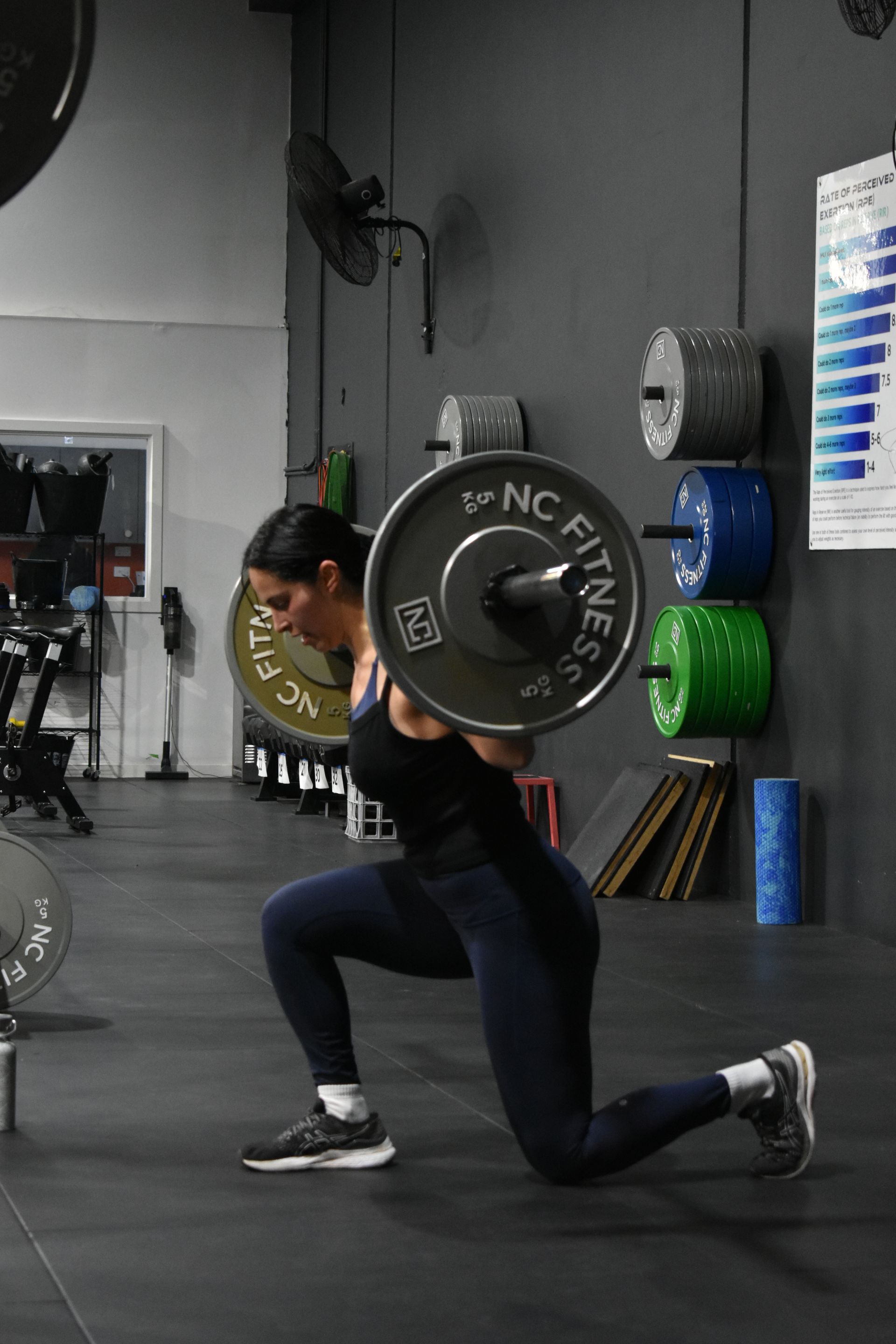 A woman is squatting with a barbell in a gym.