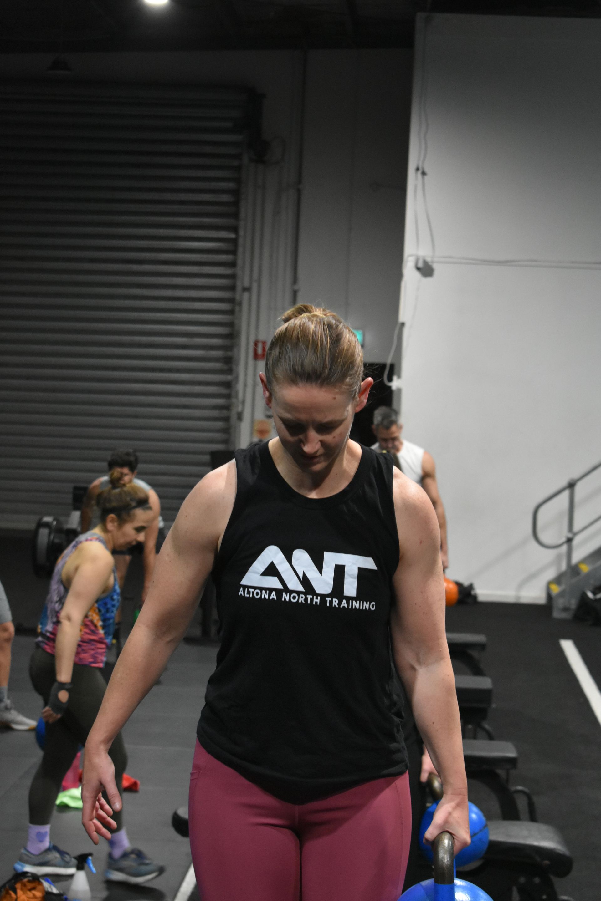 A woman wearing a black tank top with the word ant on it