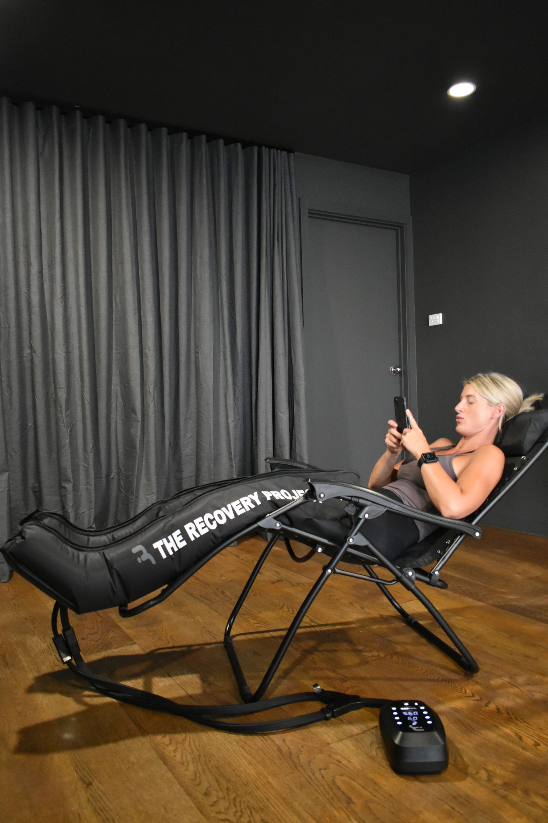 A woman is sitting in a chair using a cell phone.