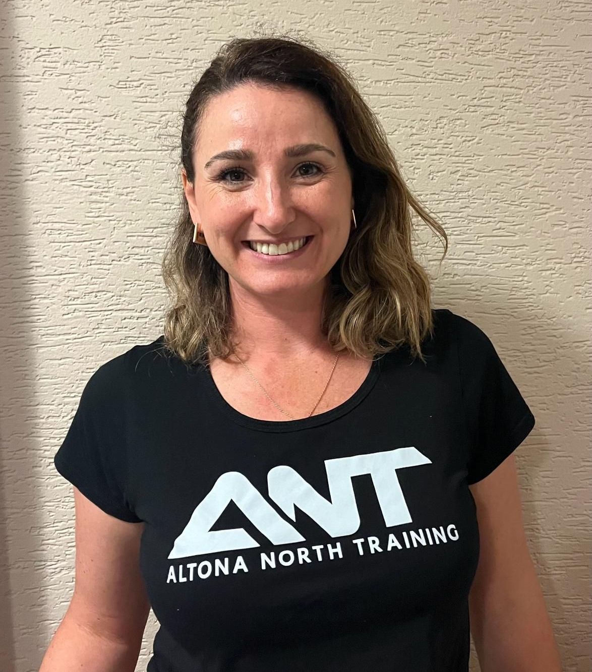 A woman is wearing a black ant t-shirt and smiling.