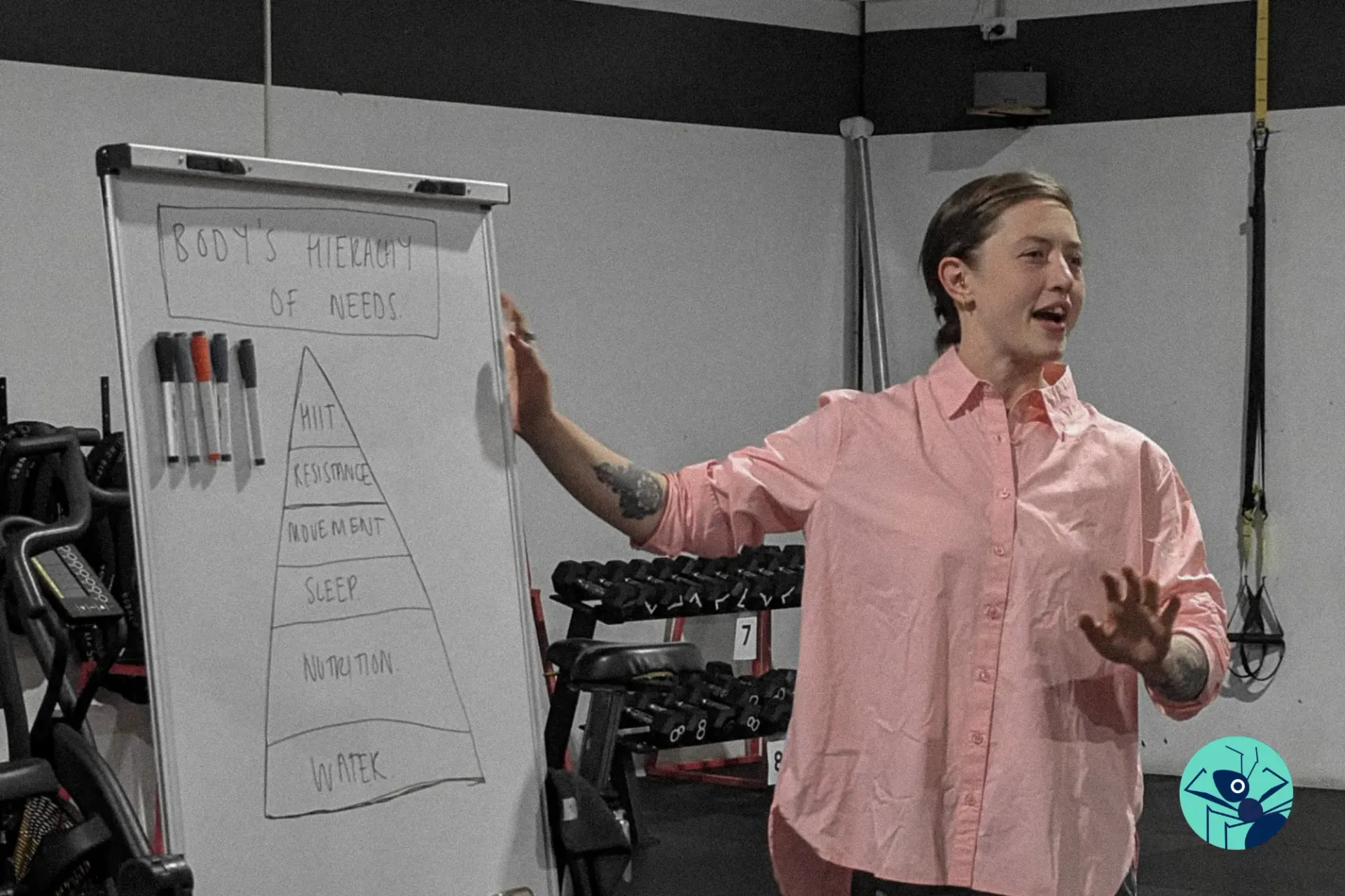 A woman in a pink shirt is standing in front of a white board.