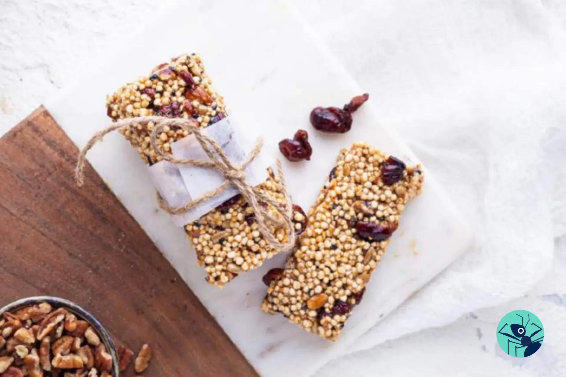 Two granola bars with nuts and cranberries on a cutting board.