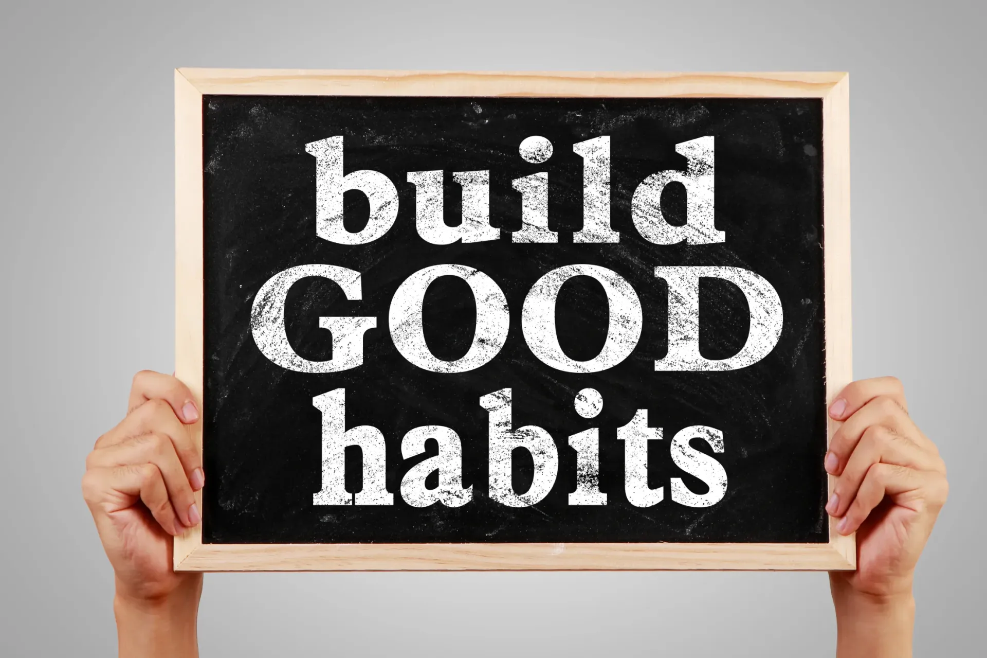 A person is holding a sign that says build good habits
