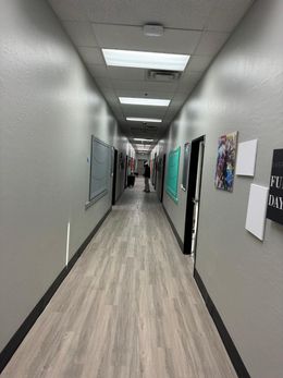 Unfinished white hallway in a building under construction, with exposed wiring and door openings.