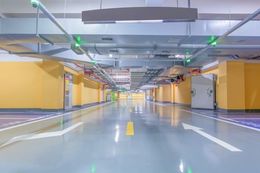 Empty underground parking garage with yellow walls, polished floor, and overhead lighting