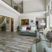 Bright modern living room with gray sofas, wood floors, and a lofted second floor railing