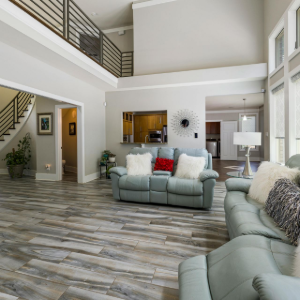 Bright modern living room with gray sofas, wood floors, and a lofted second floor railing