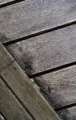 Weathered wooden planks with dark diagonal beams and small bolts.