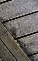 Weathered wooden planks with dark diagonal beams and small bolts.