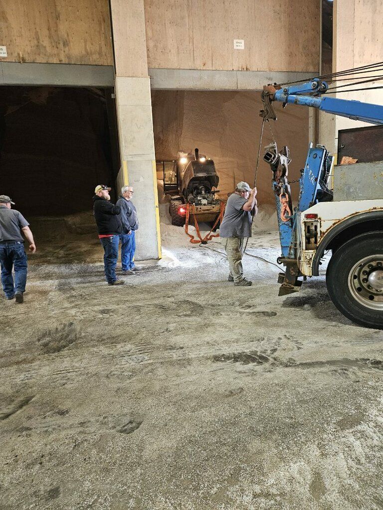 Construction workers near a garage entrance, guiding a crane over a wet concrete floor.