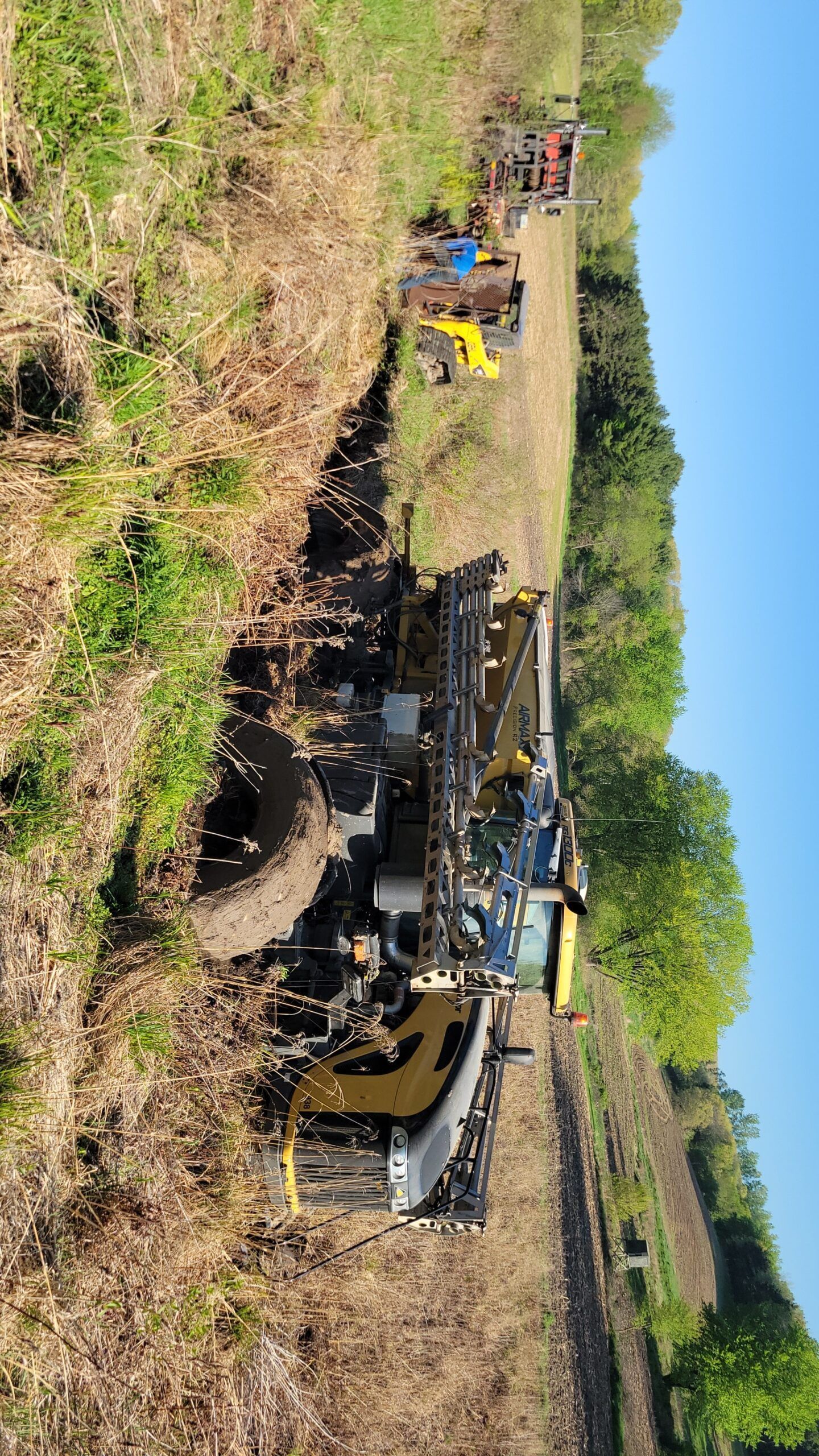 Heavy machinery clearing earth in a dry field under a bright blue sky