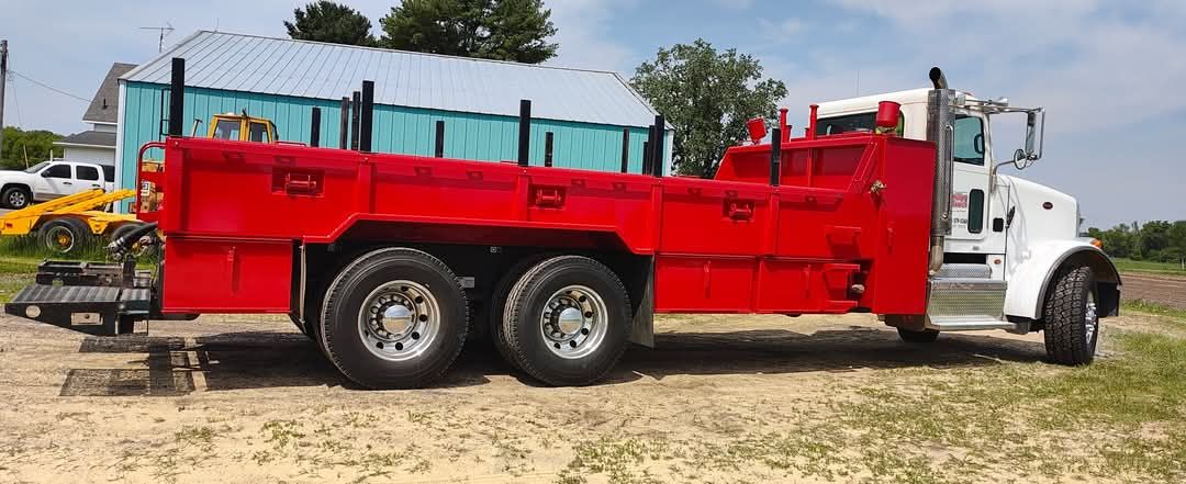 Red heavy-duty utility truck with large red equipment box parked on a dirt lot