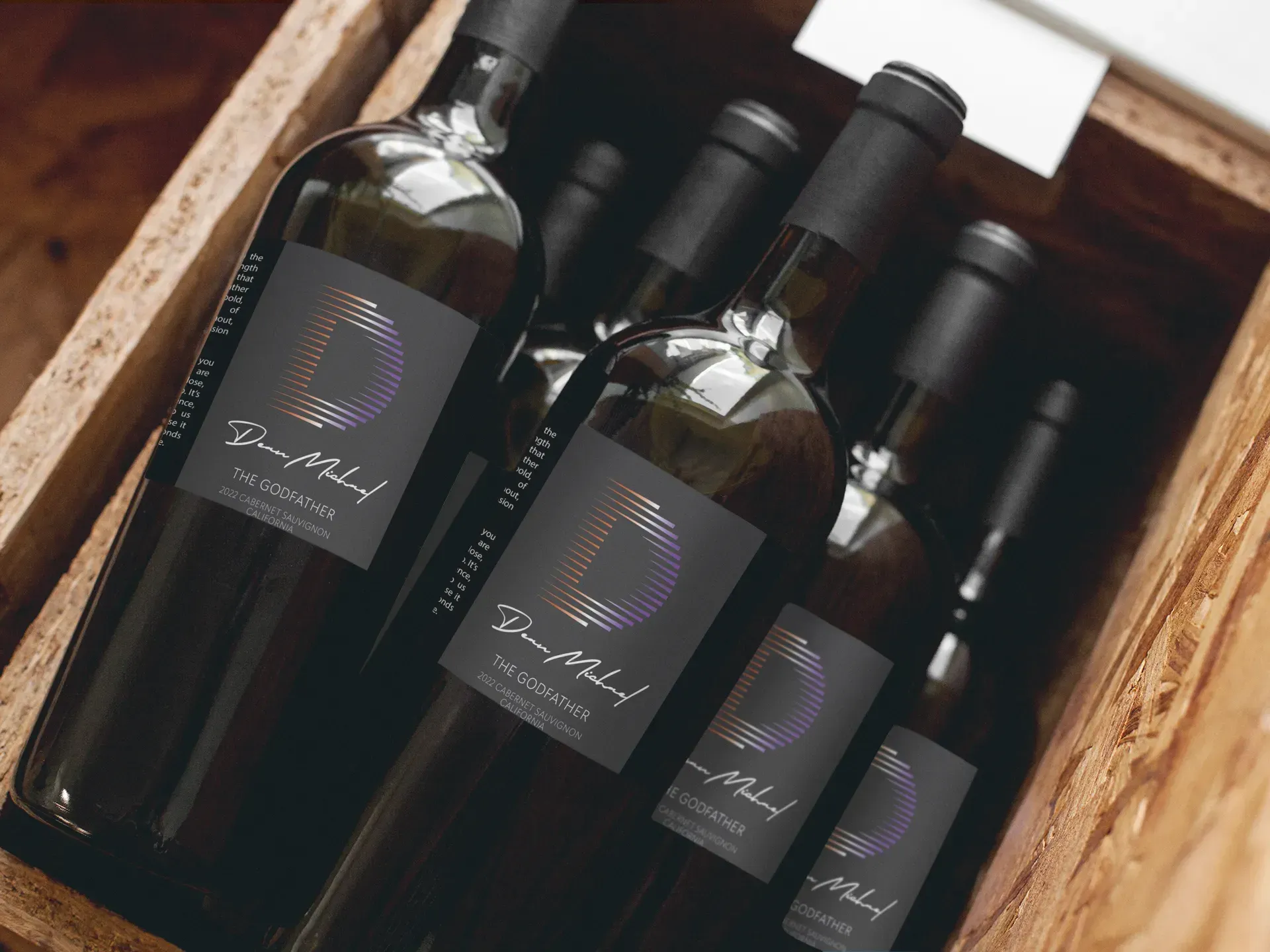Several wine bottles with dark, branded labels featuring a circular logo rest inside a wooden crate.