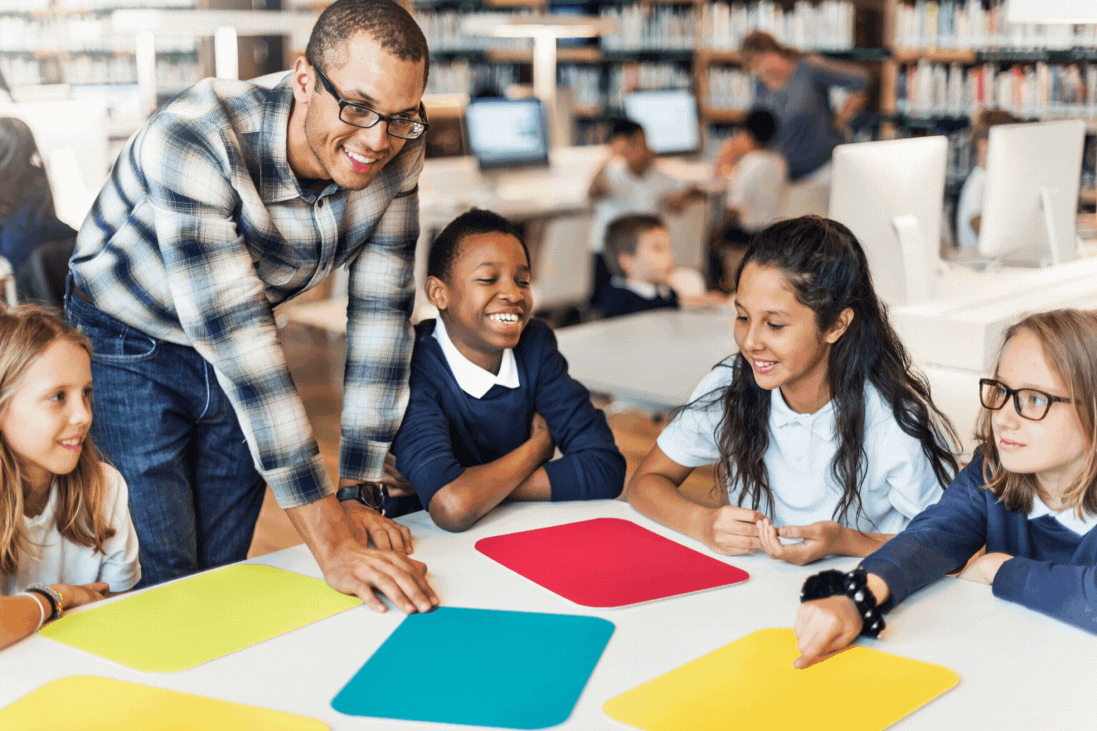 A group of children are sitting at a table with a teacher.