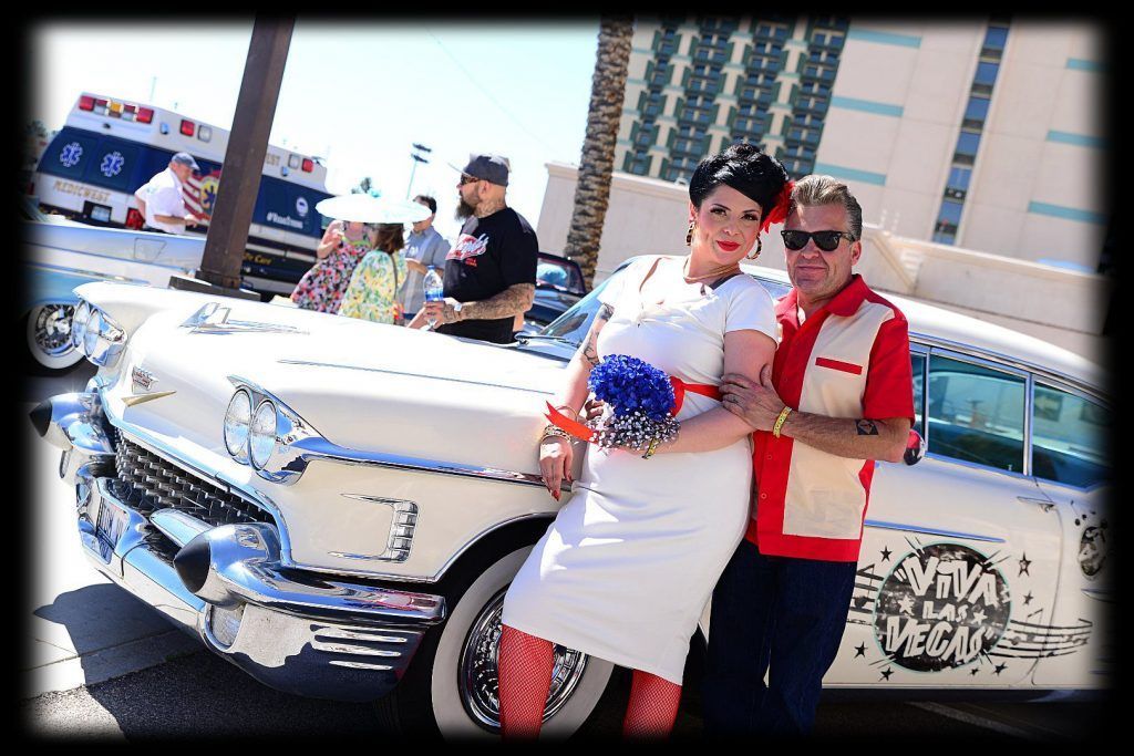 Two people posing beside a white vintage car at a Rockabilly Car Show in Las Vegas, with The Orleans Hotel in the background.