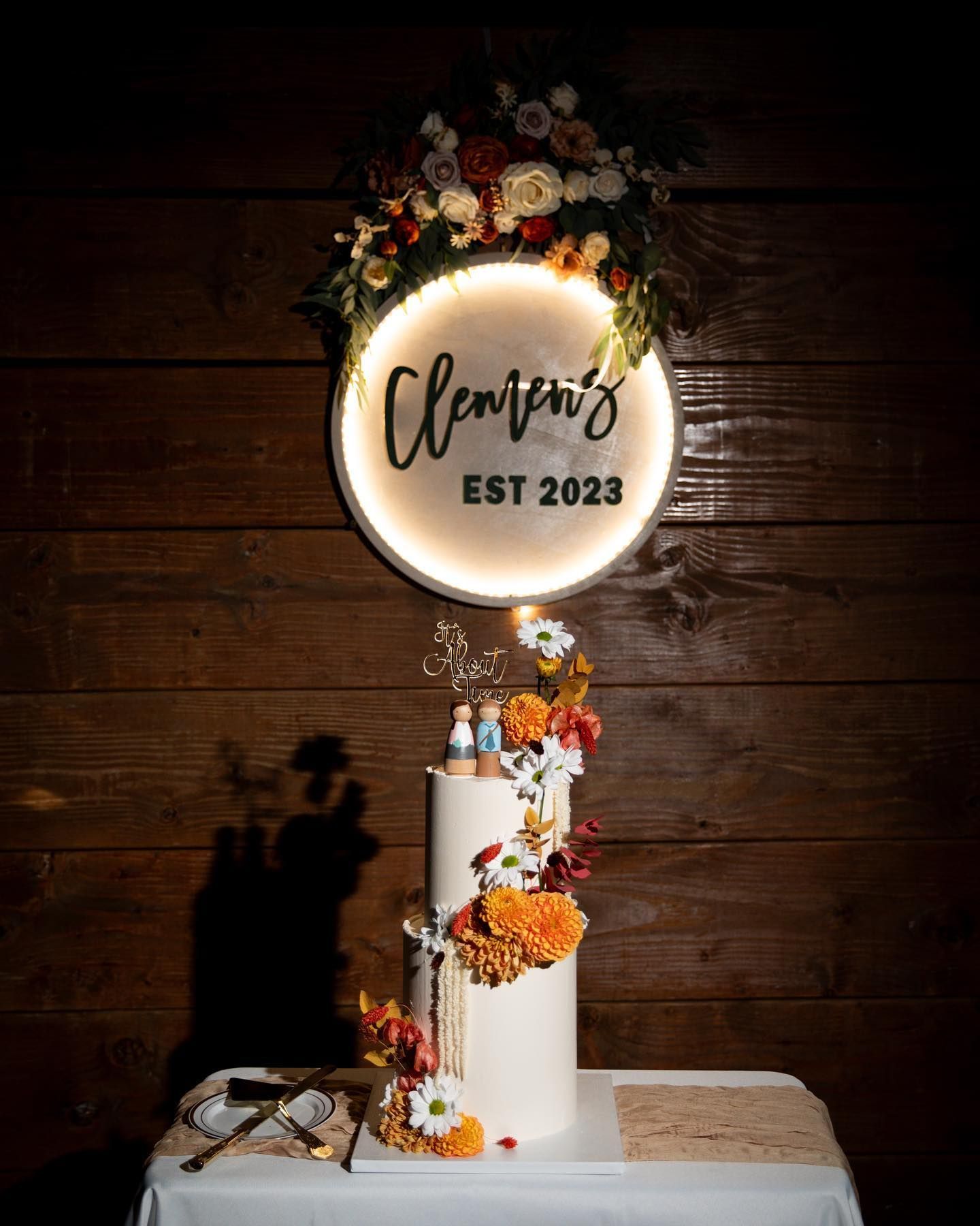 A cake is sitting on a table in front of a wooden wall.