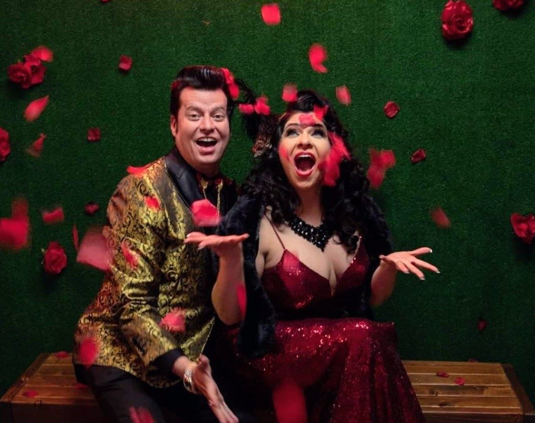 A man and a woman are sitting on a bench with petals falling around them.