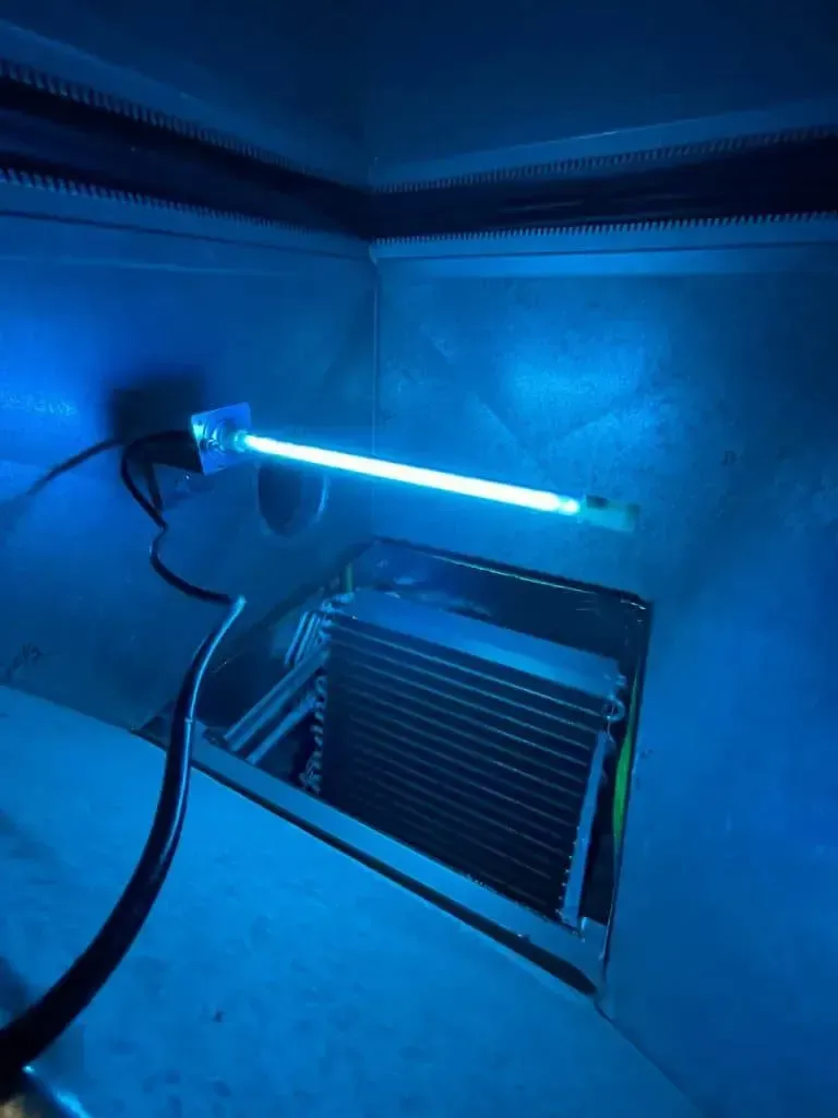 Blue UV light inside an air handler unit, illuminating the cooling coils.