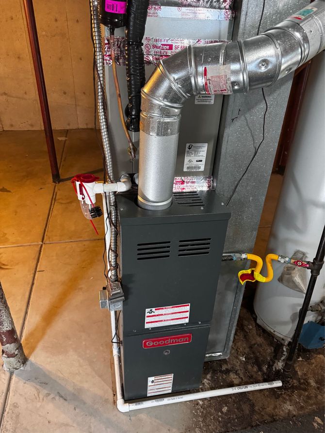 Furnace system with silver ductwork, pipes, and gas lines in a basement setting.