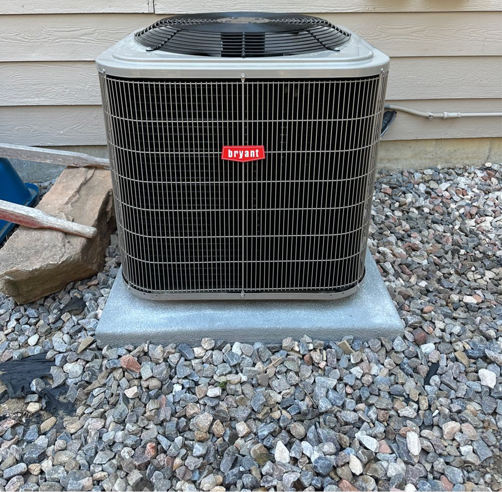 A woman is working on an air conditioner outside of a brick building.