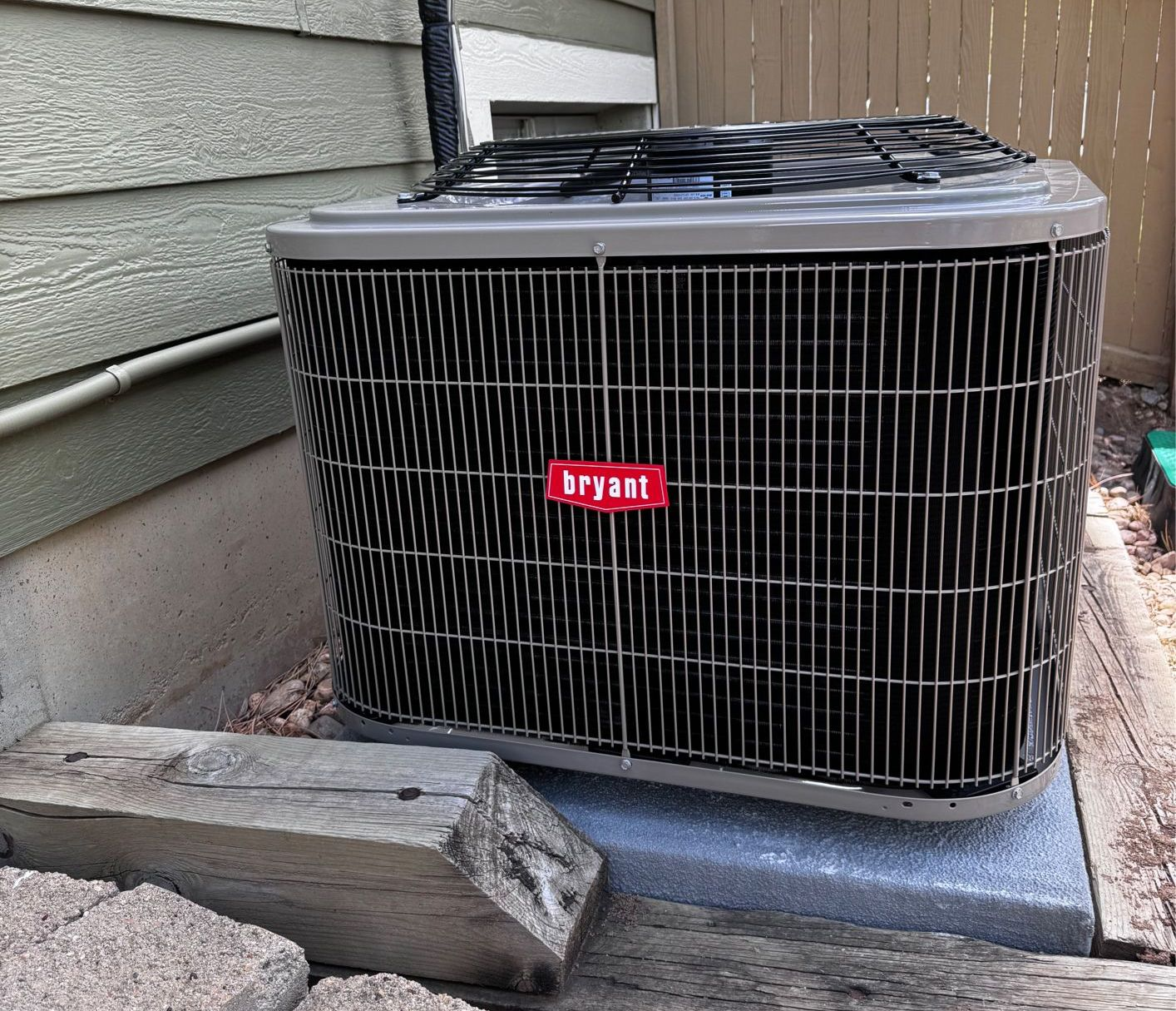 An air conditioner is sitting on the side of a house.