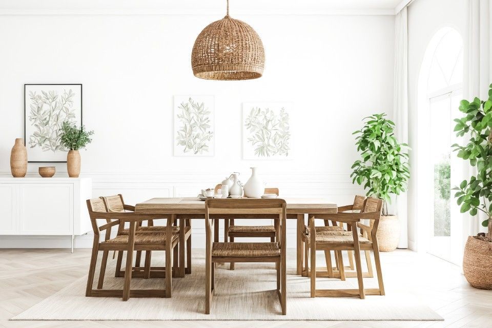 Bright dining room with wooden table and chairs, woven pendant light, and plants by large windows