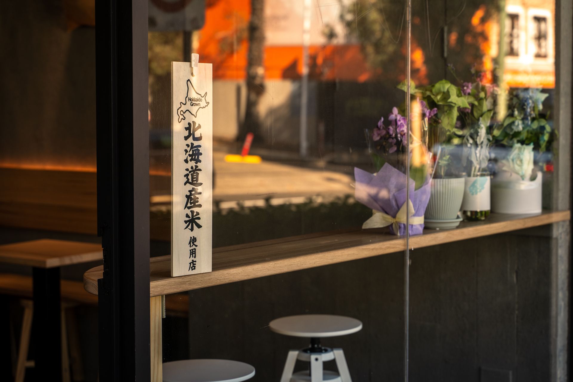 A window with a wooden shelf and flowers on it.