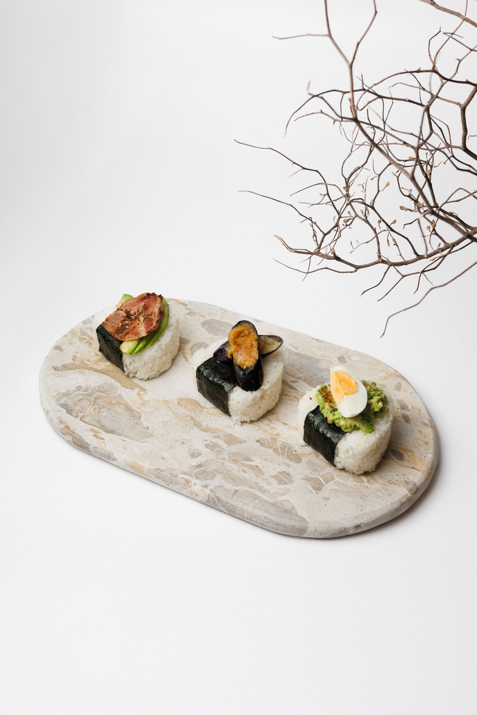 Three different types of onigiri are on a marble tray.