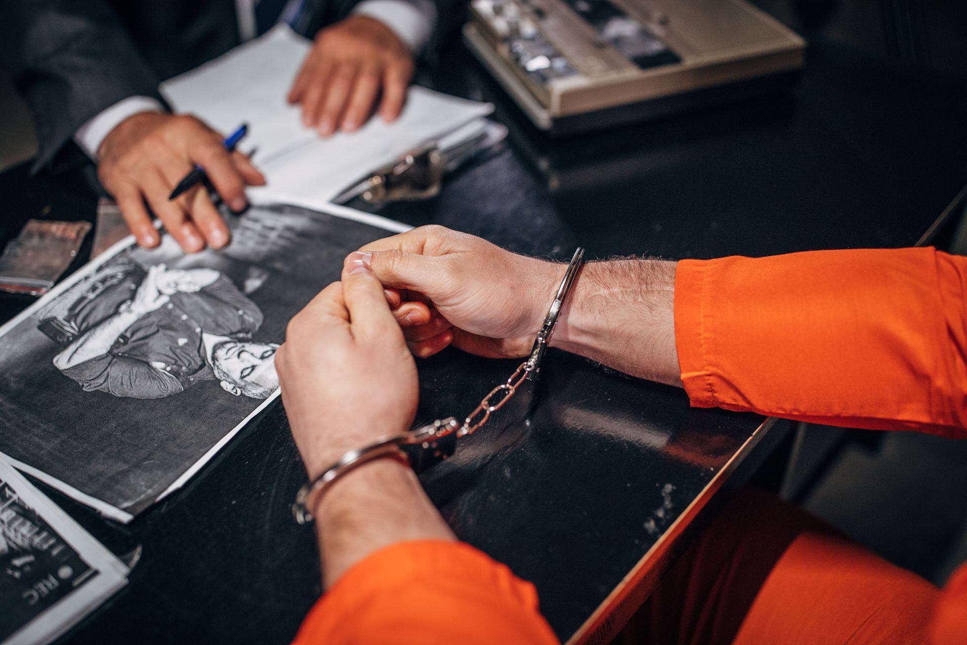 A man in handcuffs is sitting at a table looking at a picture.