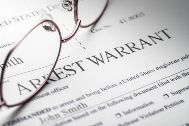 Glasses on top of a arrest warrant form.