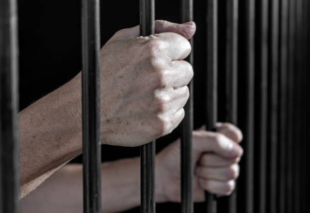 Hands holding a prison bars.