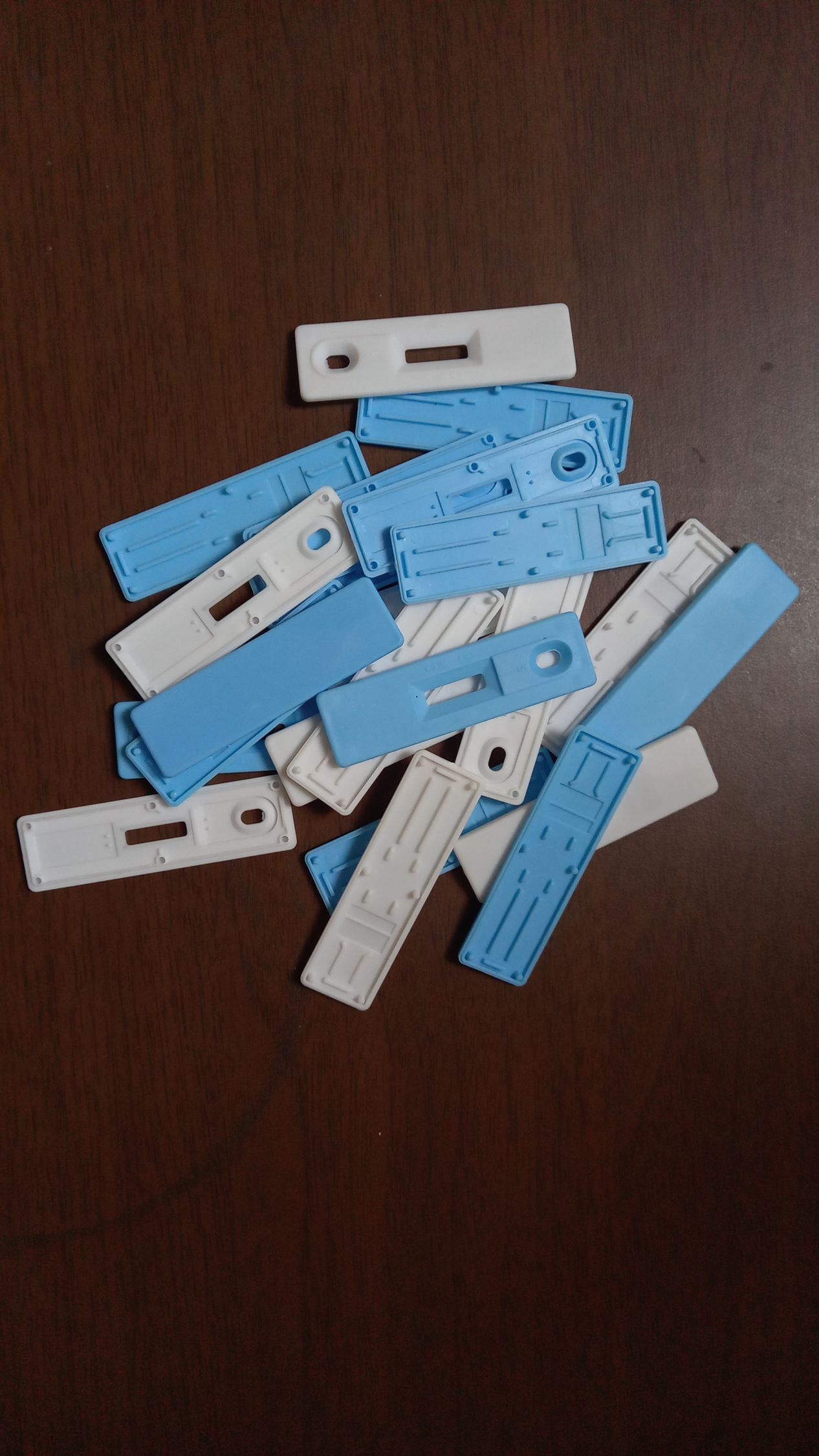Un montón de pinzas de ropa de plástico azules y blancas sobre una superficie de madera oscura.