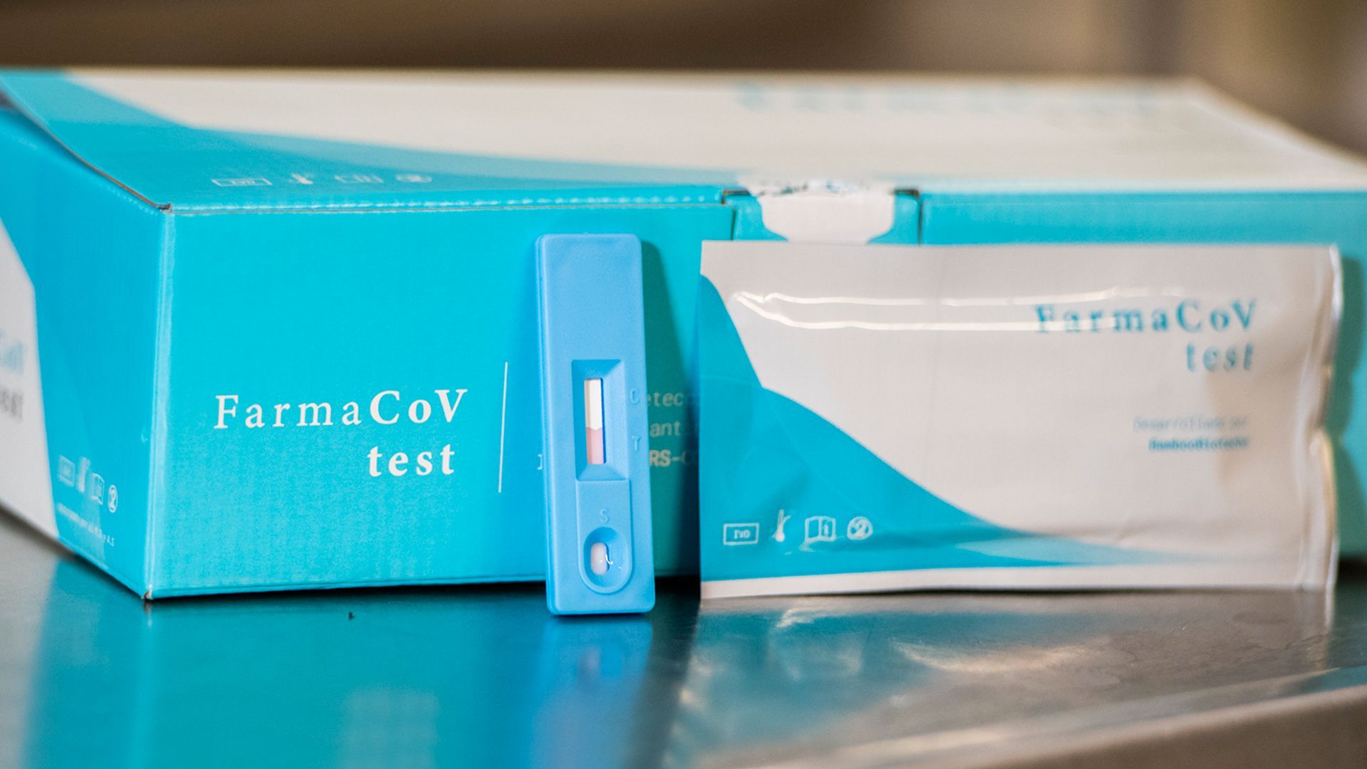 Caja del kit de prueba FarmaCoV con un dispositivo de prueba azul y una bolsa de muestra sellada
