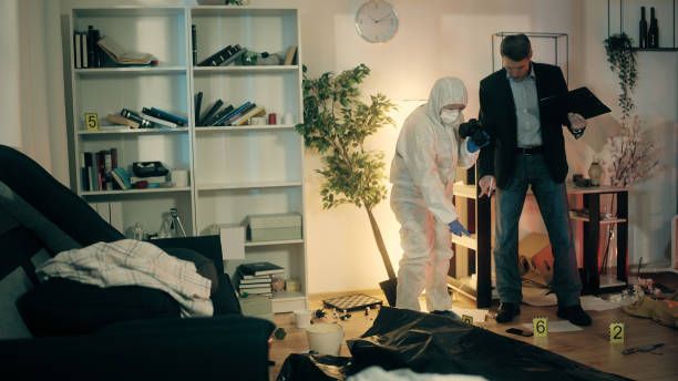 Forensic investigators examining a living room crime scene beside evidence markers and a body on the floor