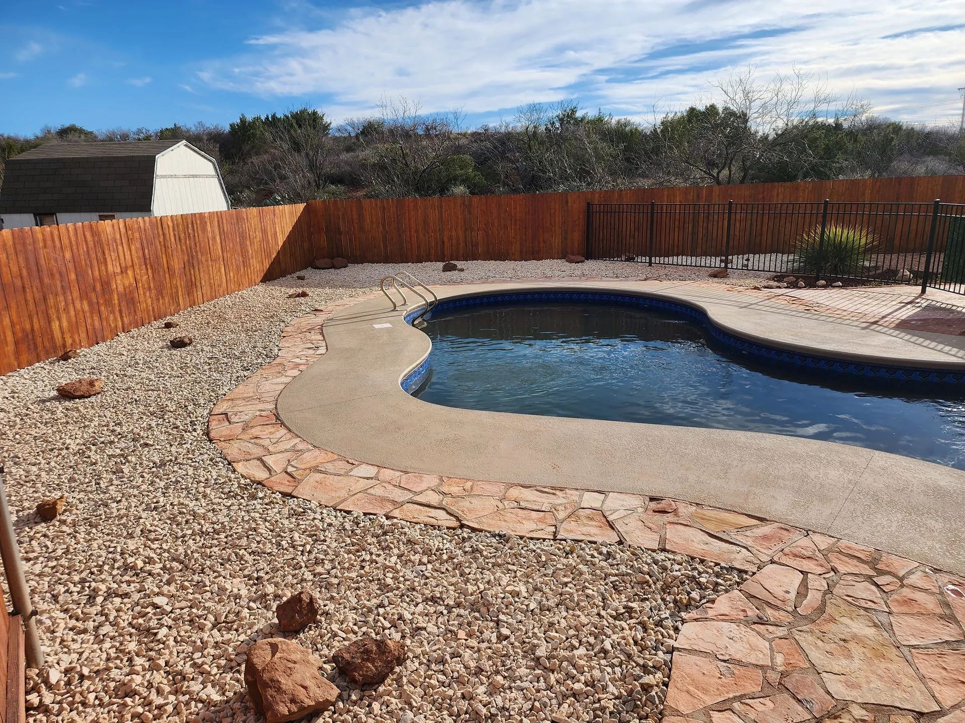a large swimming pool with a wooden fence around it