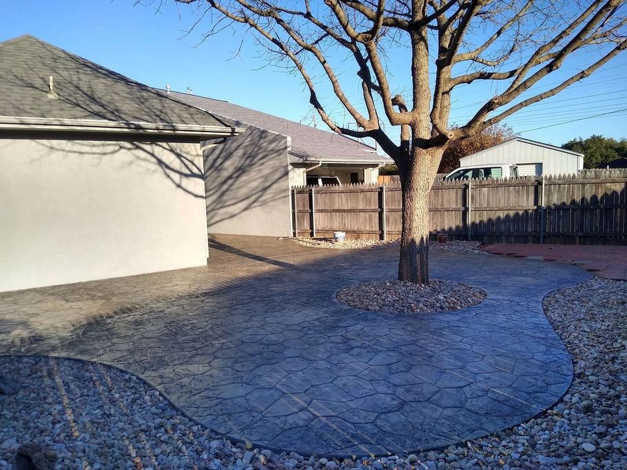 a tree is in the middle of a concrete patio in front of a house