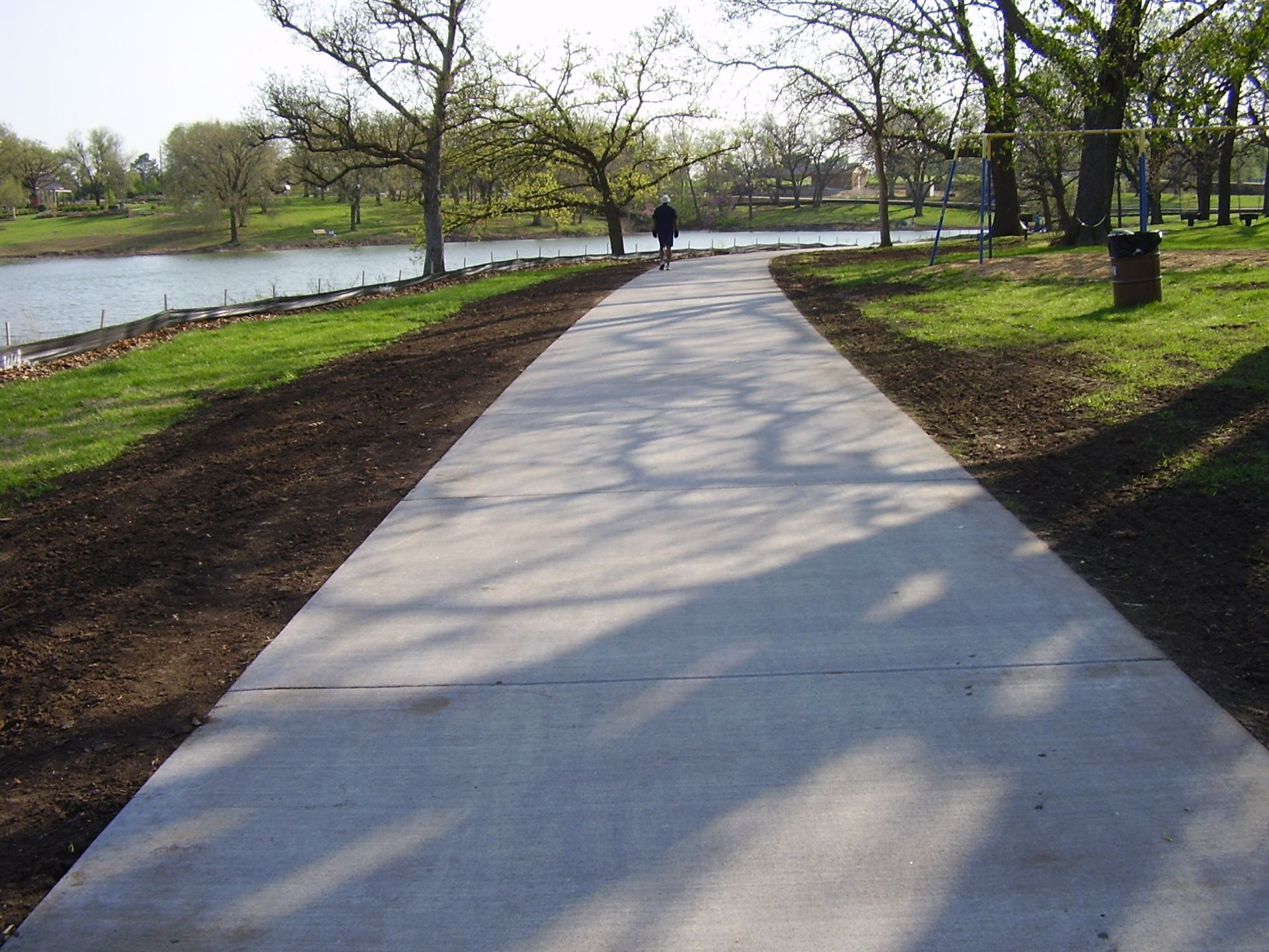 A person walking down a concrete path in a park