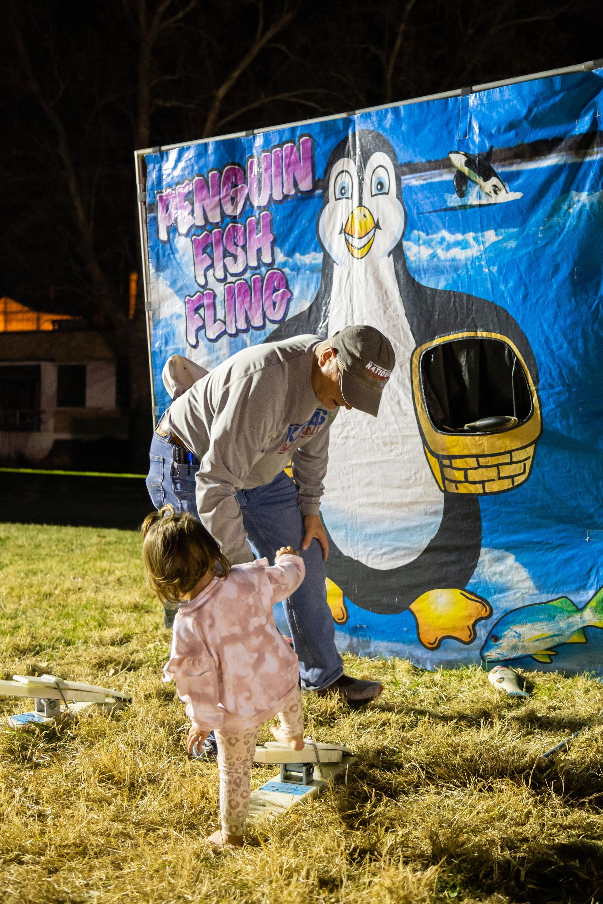 A man helps a small child play a game at the Fall Family Picnic for ICL.