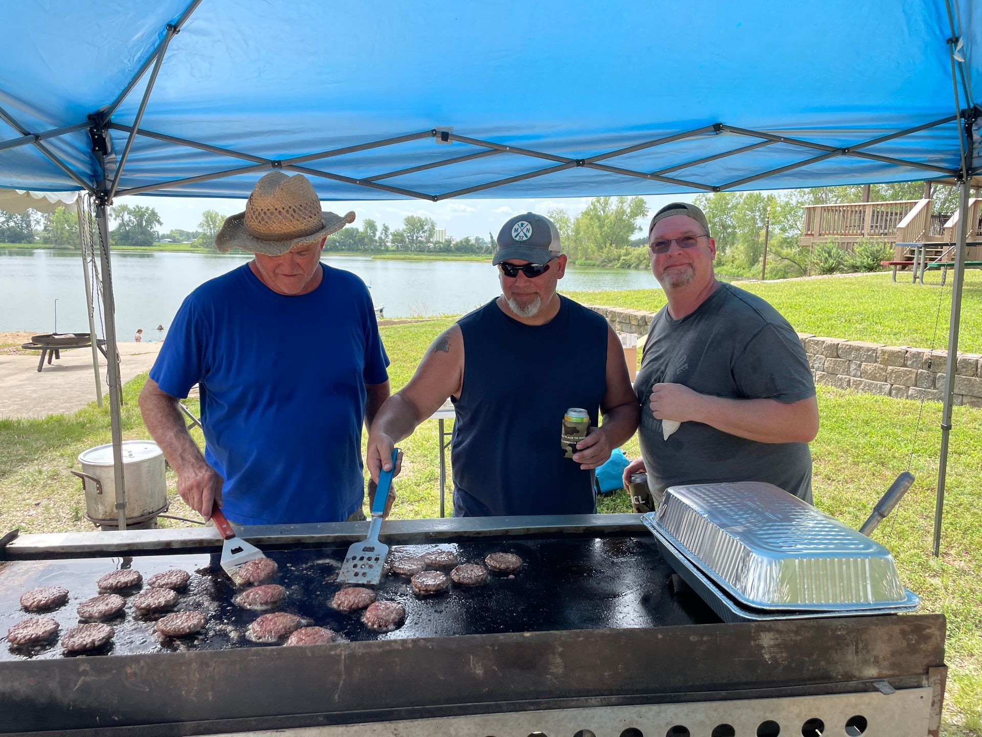 ICL summer picnic with people standing under a tent and grilling meat.