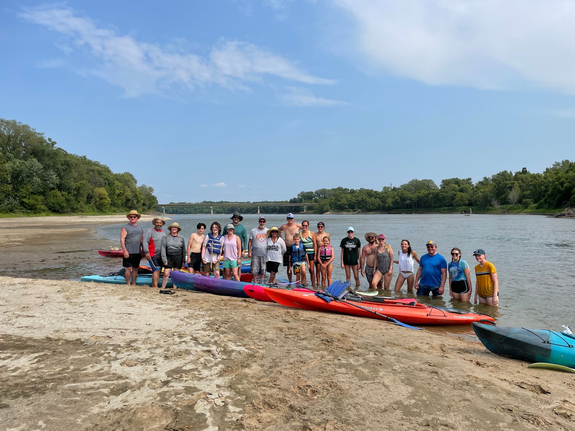 a group of icl employees are standing on a beach next to kayaks .